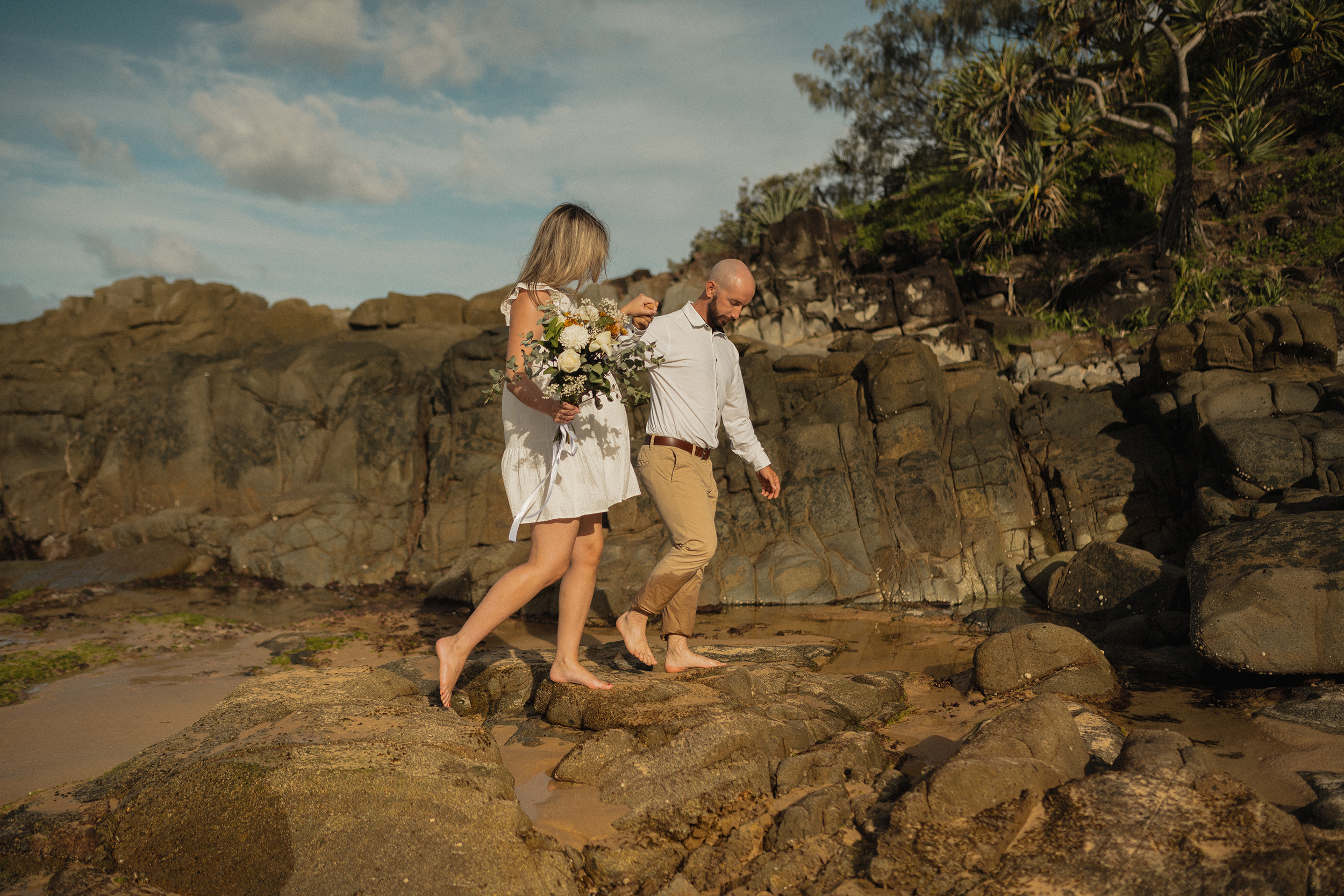 Couple on dramatic coastal rocks with bouquet